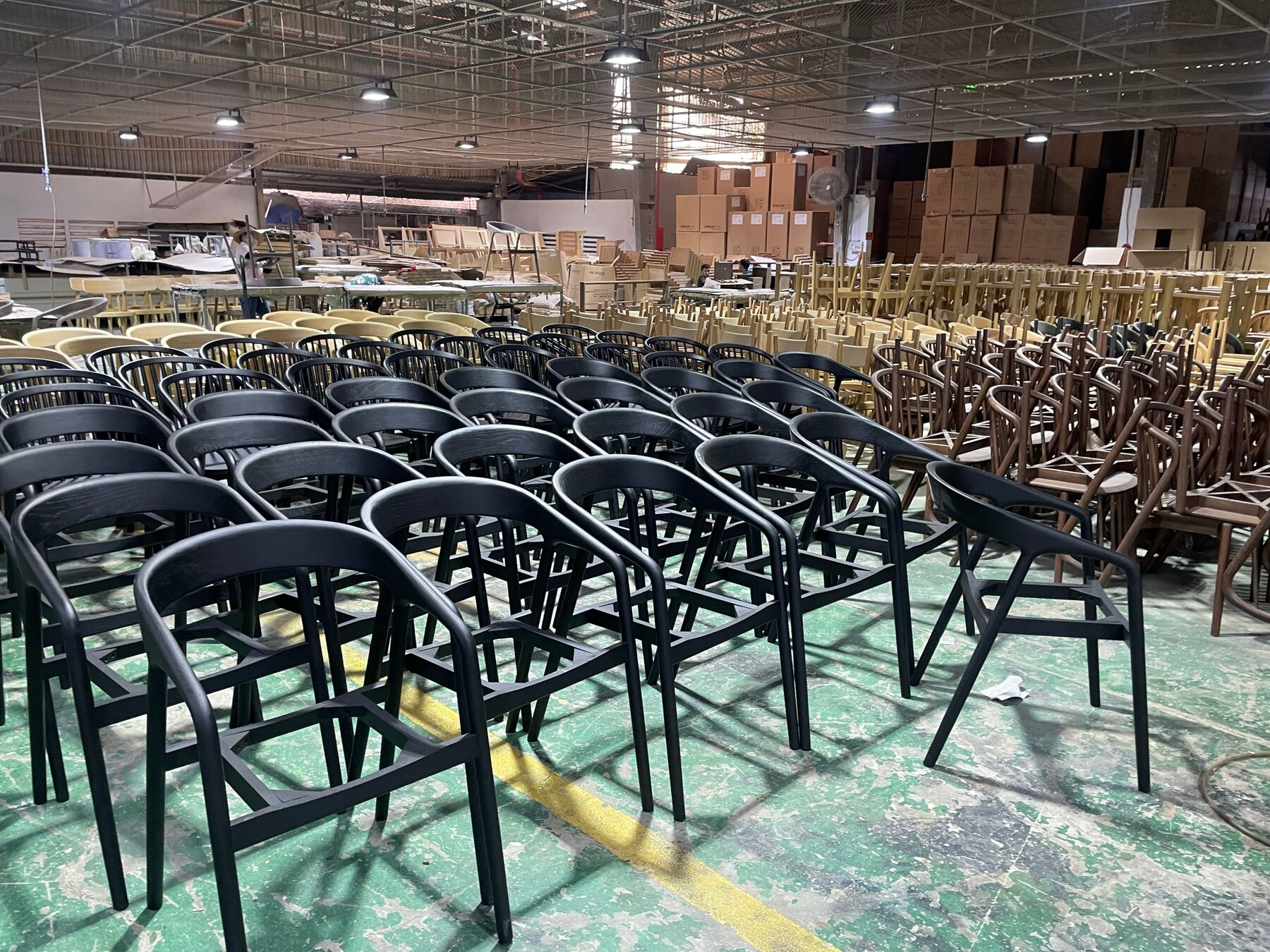 Rows of finished black oak armchairs on a Vietnamese factory floor